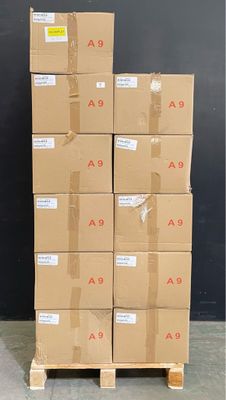 des cartons empilés sur des palettes devant un mur noir