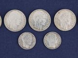 six different types of silver coins on a blue surface