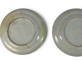 pair of white and green plates on a white surface with a white background