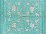 une écharpe à motifs floraux bleus et blancs, bordée d'or