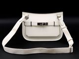 a white leather bag with a metal clasp on a black background