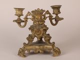 an antique brass candelab with two candles on a stand