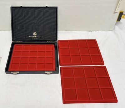 trois plateaux rouges posés sur une table, à côté d'une mallette noire