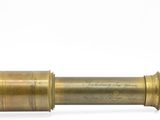 un télescope ancien en laiton posé sur une surface blanche, avec un fond blanc