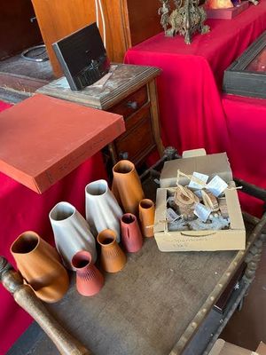 many vases sitting on a table with a red table cloth