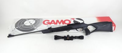 a close up of a rifle with a scope and a box of gamo