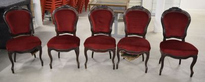 Six chaises rouges sont alignées en rang dans une pièce