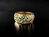 a close up of a gold ring with green stones