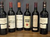 six bottles of wine are lined up on a wooden table