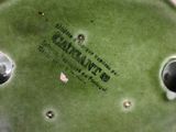 a green vase with a label on it sitting on a table