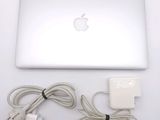 an apple laptop computer sitting on top of a white table next to a charger