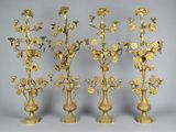 four gold colored vases with flowers in them