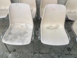 plusieurs chaises blanches sont alignées sur un trottoir