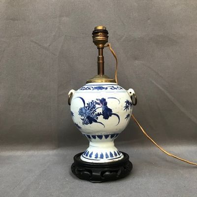 une photo d'une lampe en forme de vase bleu et blanc posée sur un pied noir