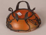 an orange bowl with a black handle on a white surface