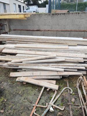 un tas de bois posé sur le sol à côté d'un bâtiment