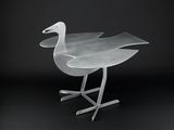 a metal bird that is sitting on a metal stand