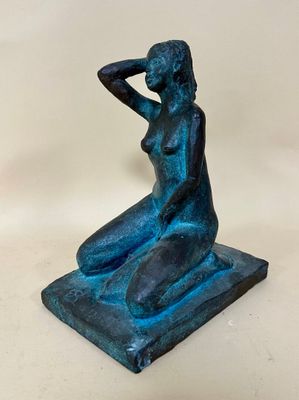 a blue statue of a woman sitting on a square base