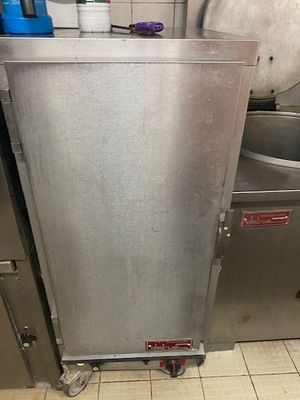 une grande armoire métallique dans une cuisine, avec un seau posé par terre