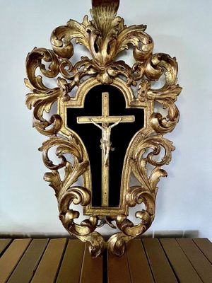 une croix en or posée sur une table en bois devant un mur blanc
