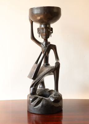 statue d'une femme tenant un bol sur la tête