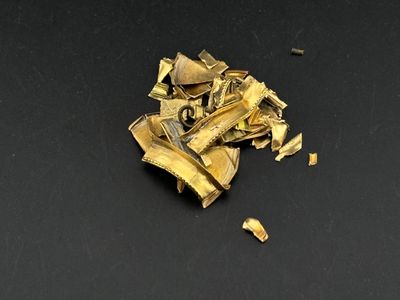 a pile of gold pieces on a black surface