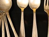 five silver spoons and two silver spoons on a black tray