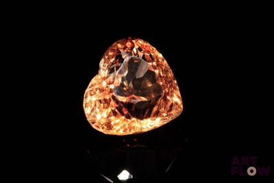 a close up of a diamond on a black surface with a black background