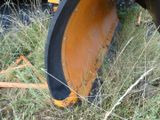a tractor that is sitting in the grass with a plow behind it