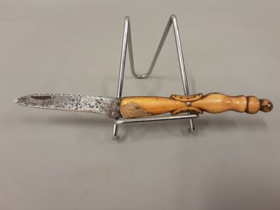 a close up of a knife with a wooden handle on a metal stand