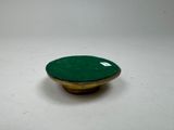 a green button on a white surface with a white tag on it