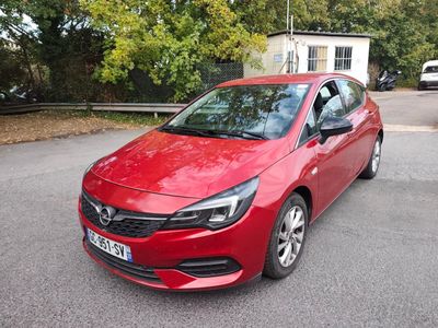 La voiture rouge est garée sur le bord de la route, devant une maison.