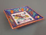 an orange and blue plate with a floral design on it