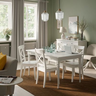 une table et des chaises blanches dans une pièce aux murs verts