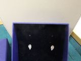 pair of diamond stud earrings in a purple box on a blue surface