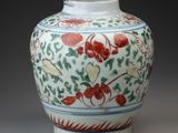 a white vase with red and green designs on it