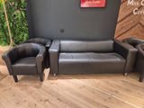 un canapé, un fauteuil et un pouf dans un coin de la pièce