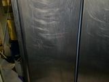 a large stainless steel refrigerator in a kitchen with a trash can