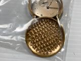 a small gold pocket watch sitting on a plastic bag