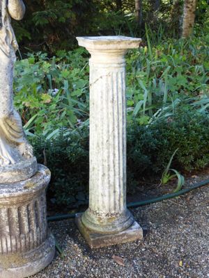 une statue représentant une femme tenant un oiseau près d'un pilier