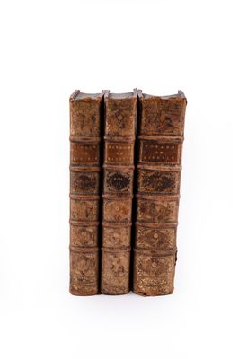 three old books sitting on top of each other on a white surface