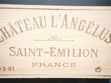une caisse en bois sur laquelle est accrochée une pancarte indiquant « Château L'Angélus Saint-Emilio »