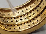 a close up of a gold ring with holes on it