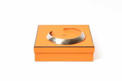 une boîte orange sur laquelle est posé un bracelet argenté