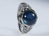 gros plan d'une bague avec une pierre bleue entourée de diamants