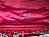 a pair of silver shoes in a box on a red cloth