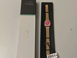 une photo d'une montre en or avec un cadran rose, dans un coffret