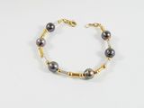 un bracelet composé de perles noires et de perles dorées sur fond blanc