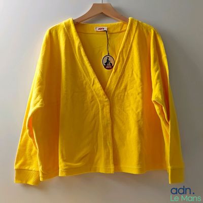 La chemise jaune est suspendue à un cintre accroché au mur.