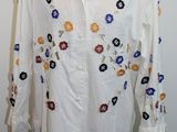 une image représentant une chemise blanche ornée de fleurs colorées